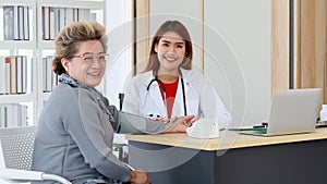 Asian senior elderly woman and doctor smiling and look at camera both of them look happy. Elder woman wearing sphygmomanometer to