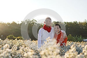 Asian senior eldery couple hugging sweater celecrate Christmas and New Year holiday morning in beautiful flowers garden
