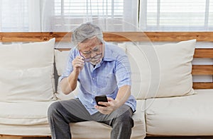 Asian senior fatigue man taking off glasses during using smartphone