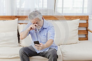 Asian senior fatigue man taking off glasses during using smartphone