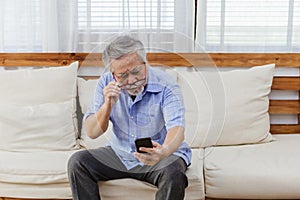 Asian senior fatigue man taking off glasses during using smartphone