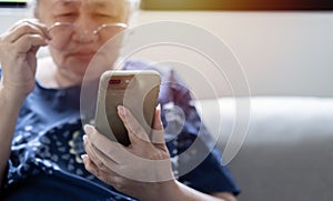 Asian senior fatigue woman taking off eye glasses during using smartphone after surfing internet at home