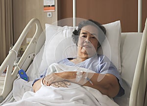 Asian senior female patient  lying down  in hospital bed, looking at camera. Elderly health concept