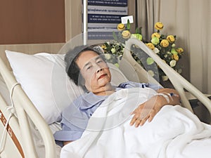 Asian senior female patient  lying down  in hospital bed, looking at camera. Elderly health concept