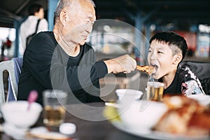 Asian senior Granfather feeding her grandson in restaurant