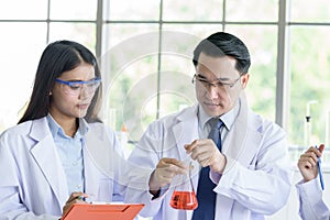 Asian senior laboratory scientist man working at lab with asian young student scientist backgroud