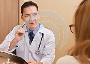 Asian Senior male Doctor talking to female patient.