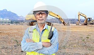Asian senior male engineer wearing safety vest and helmet inspects civil works The chief construction engineer uses a walkie-
