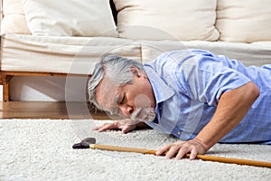 Asian senior man falling down on carpet and lying on the floor in living room at home.