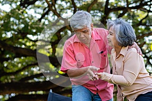 Asian senior man falling down on lying floor at park after Stumbled  and Crying in pain and him wife came to help support. Concept