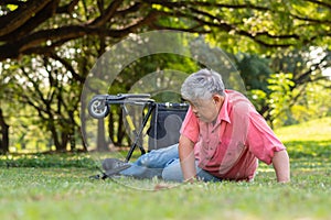 Asian senior man falling down from wheelchair on lying floor after trying push the wheelchair forward and Crying in pain and