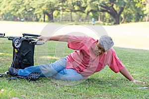 Asian senior man falling down from wheelchair on lying floor after trying push the wheelchair forward and Crying in pain and