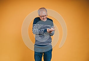 Asian senior man feeling wrist pain on the yellow background