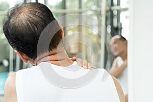 Asian senior man having pain on his shoulder and neck.