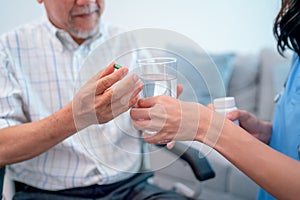 Asian senior man hold medicine pill and discuss with nurse or doctor during homecare service