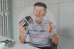 Asian senior man, Holding VR glasses with Feeling happy for modern technology.