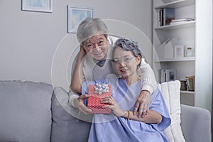 Asian senior man husband giving present gift box for Valentine`s day to happy surprised wife
