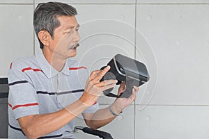 Asian senior man. Interested to VR glasses, modern technology. Look at to that and Thinking something