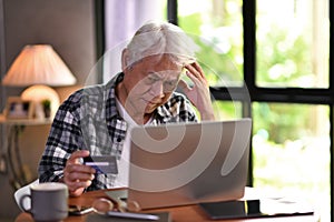 Asian senior man looking confuse when using credit card for online shopping