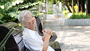 Asian senior man relaxing in the park laughing in sunshine