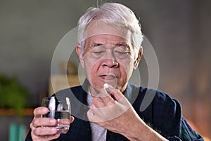 Asian senior man taking pills at home