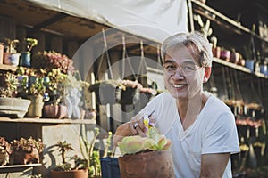 asian senior man toothy smile with happiness face holding succulent plant in hand