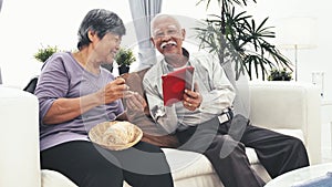 Asian senior man using tablet computer and Senior woman hand craft knitting wool at home.