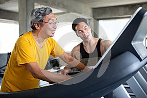 asian Senior man walking exercise on treadmill with Personal trainer workout in fitness gym . sport trainnig , retired , older ,