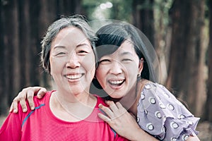 Asian senior mother and her adult daughter are hugging