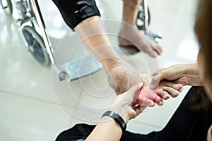 Asian senior mother in wheelchair,receiving a foot massage from her daughter,physiology pressing with fingers to relax,old woman