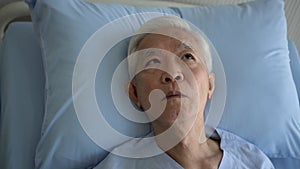 Asian senior old sick man worry fear uncomfortable facial expression on hospital bed