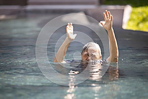 Asian senior people struggling underwater, hand peeking out of the water, female drowned in swimming pool, drowning elderly woman