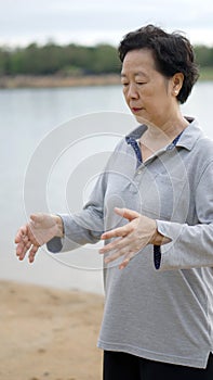 Asian Senior Practice Taichi, Qi Gong exercise next to the lake photo