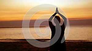 Asian senior silhouette doing meditation namaste at sunrise beach