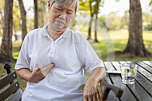 Asian senior woman with acid reflux disease symptoms or heartburn, sad female elderly suffering from symptomatic indigestion or photo