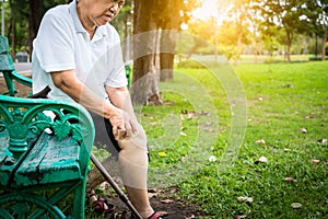 Asian senior woman arthritis,osteoarthritis,elderly people sitting,holding hand on the knee in park,feeling pain in the knee,