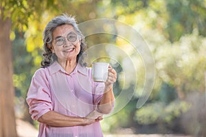 asian senior woman with coffee and looking at camera