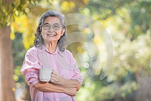 asian senior woman with coffee and looking at camera
