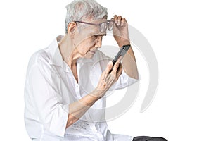 Asian senior woman with eye glasses,try to read messages,gaze at the small text on mobile phone,age related macular degeneration,