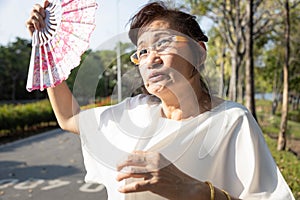 Asian senior woman fanning and sweat on face suffer from sunburn very hot in summer weather problem feel faint, tired female