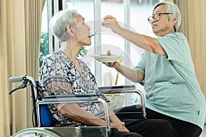 Asian senior woman is feeding older sister with thai food,female elderly helping her to eat and take a drug, love,care and concern