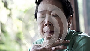 Asian senior woman with hand on face thinking, worry sad