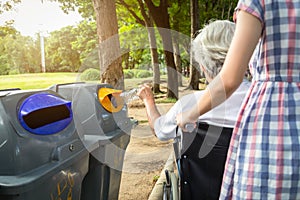 Asian senior woman hand holding plastic bottle,putting plastic water bottle in recycling bin,elderly tourist hand throwing garbage