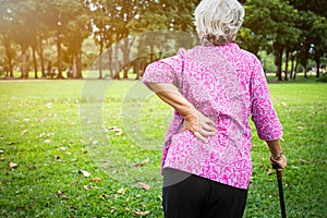 Asian senior woman hands touching back pain while walking in nature in summer,female patient having backache,muscle,hip pain in