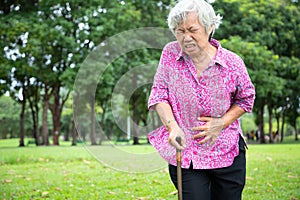 Asian senior woman hands touching stomach while walking in nature in summer,female patient having sick stomach,diarrhoea,