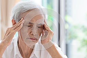Asian senior woman has headache,touching her head with her hands,communicates the symptoms of vertigo;dizziness;migraine;sick photo