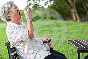 Asian senior woman has sleepy expression,elderly woman yawning covering open mouth with hand,old people feeling yawn,doze,sleepy photo