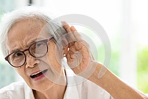 Asian senior woman listening by handÃ¢â¬â¢s up to the ear,having difficulty in hearing,elderly woman hard to hear,wear glasses with photo