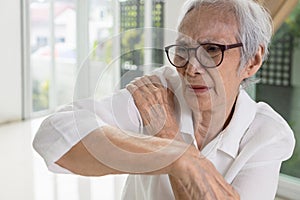 Asian senior woman massage her shoulder bone with hand,aching and tingling,old elderly patient with frozen shoulder,pain and