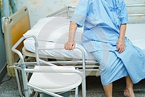 Asian senior woman patient with commode chair or mobile toilet can moving in bedroom